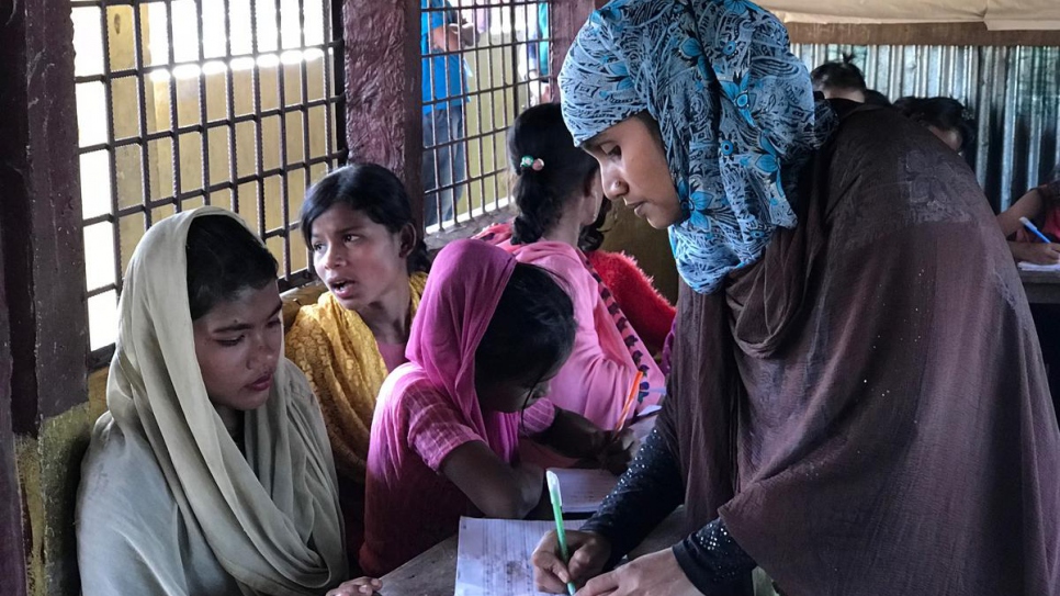 La maestra refugiada rohingya, Alinesa (32 años, no tiene apellido), corrige el trabajo de Rosina Akhter, una refugiada de 12 años recién llegada.