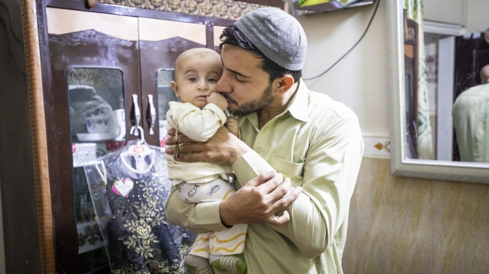 Sifat acuna a su hijo en el pequeño departamento donde vive con su familia. 