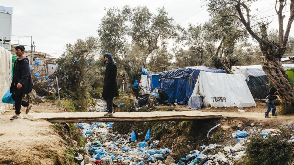 Un hombre cruza un río seco lleno de basura en un campamento improvisado colindante al centro de recepción e identificación de Moira, en la isla de Lesbos.
