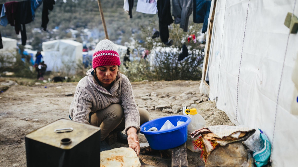 Fahima, quien huyó de Afganistán con su esposo y sus cinco hijos, hace pan en un horno improvisado fuera de la tienda de campaña de su familia, en el olivar contiguo al centro de recepción e identificación de Moira.