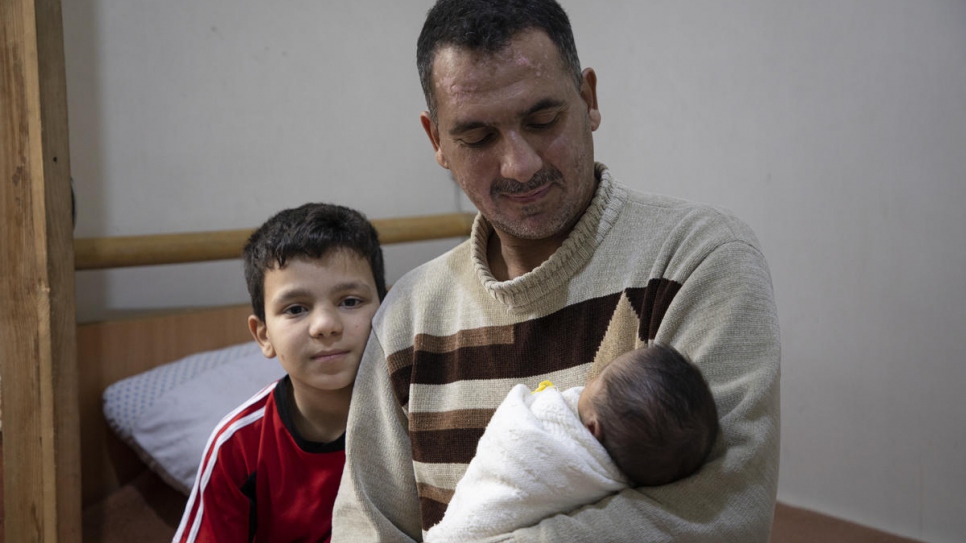 Rahib, padre de familia ex desplazado, de 45 años, carga su bebé recién nacido, Mustafa, en su casa de Alepo, Siria.