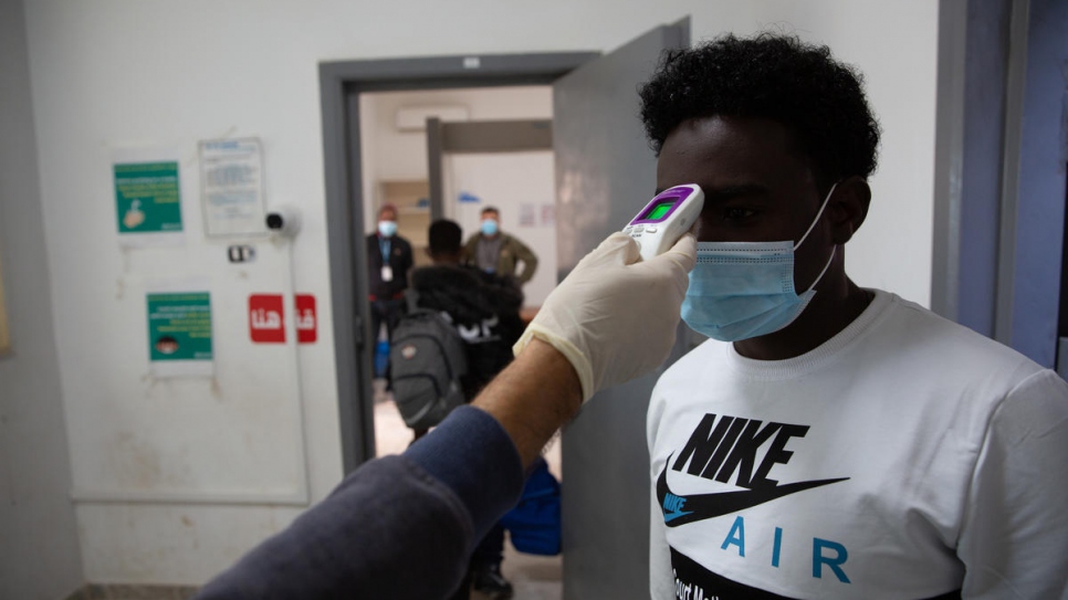 Solicitantes de asilo de Somalia, Eritrea y Sudán pasan por el control de temperatura antes de embarcarse en un vuelo de evacuación humanitaria de Libia a Ruanda.