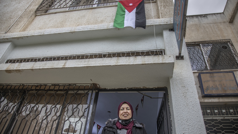 Raia Al Kabashi debajo de la bandera de Jordania en las afueras del centro de salud en Irbid, donde recibió su vacuna contra la COVID-19.