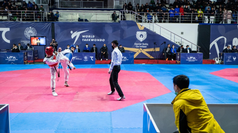 Mukhamadjon observa a uno de sus estudiantes competir en la Federación de Taekwondo.