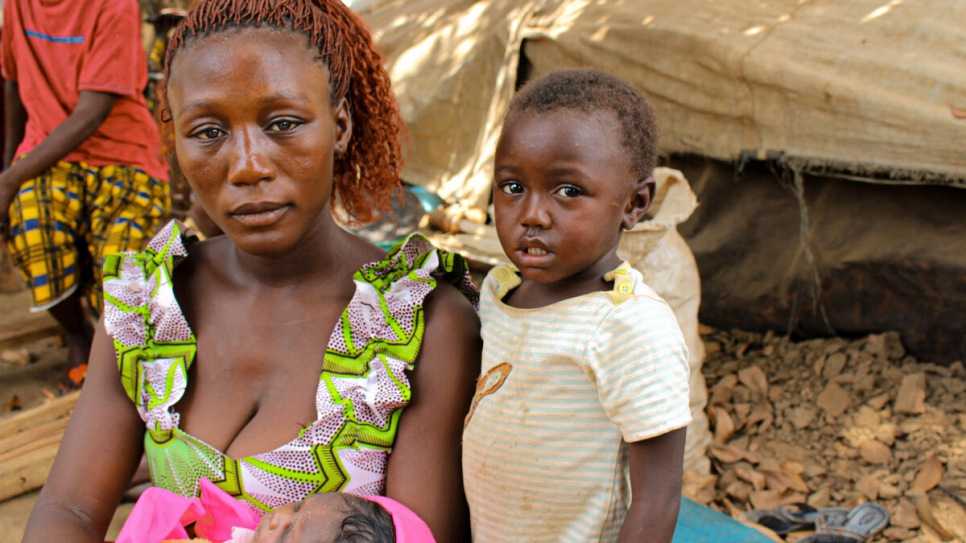 La refugiada centroafricana Benitia, de 23 años, sostiene a su bebé recién nacida mientras su hija Safira está a su lado en la aldea de Ndu en la República Democrática del Congo.