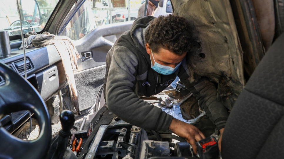 Khalil, refugiado sirio de 18 años, repara un vehículo en un taller en Amán, donde gana diez dólares al día.