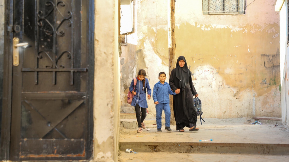Aisha de 10 años, y Ahmed de 8, caminan a casa con su tía Huda antes del reciente cierre de escuelas debido a la COVID-19.