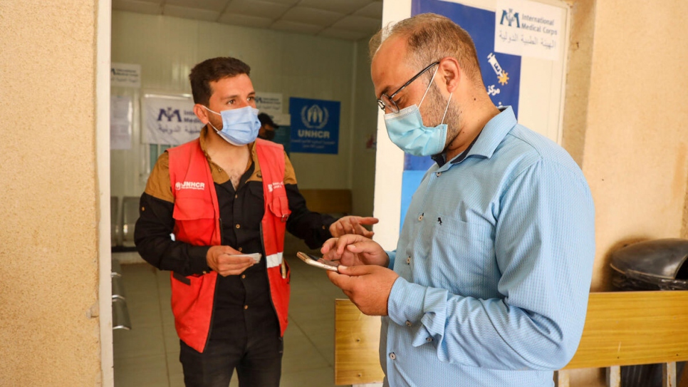 En el campamento, Sameeh de 32 años, ayuda a un compañero refugiado a registrarse para recibir la vacuna contra la COVID-19.