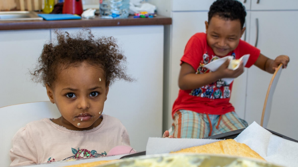Feruz (de cinco años) y Karim (de siete años) están comiendo el "tompouce" que preparó su madre en un taller de cocina organizado por AIDRom, socio de ACNUR en el Centro de Tránsito de Emergencia en Timisoara, Rumania.