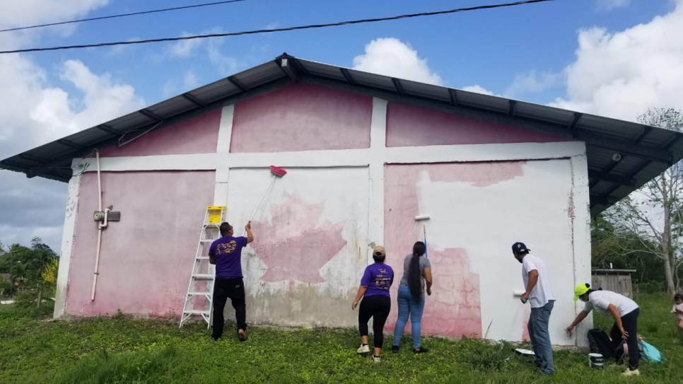 El Grupo de Mujeres Unidas y Refugiadas, junto a un pintor solicitante de asilo, comienza a limpiar la pared donde se pintará un mural para el Día Mundial del Refugiado.