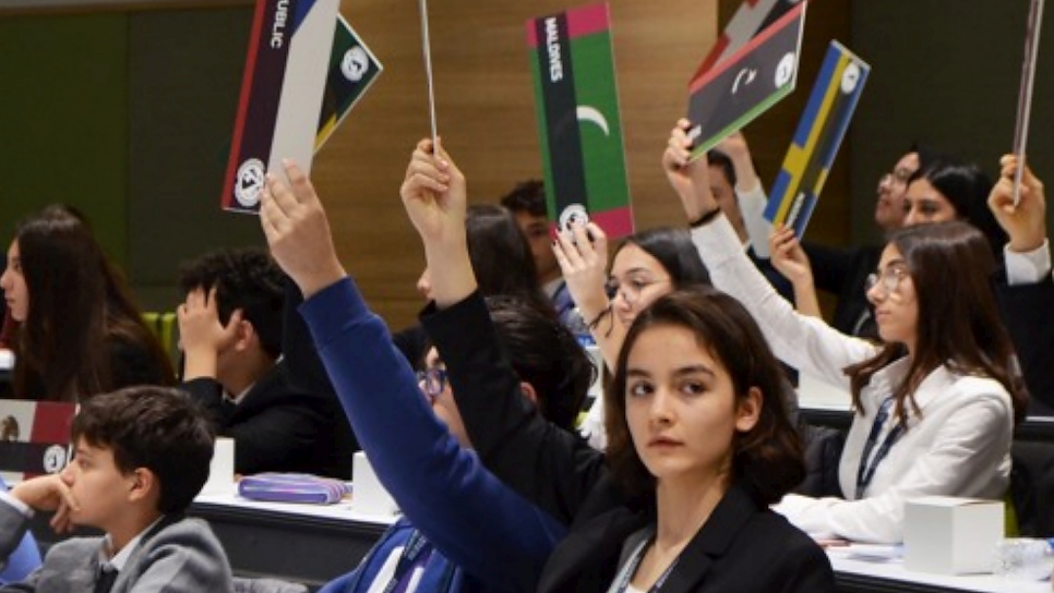 Como parte del Desafío del Modelo de la ONU sobre Refugiados, estudiantes de secundaria y preparatoria en Estambul levantan sus placas para hablar del desplazamiento provocado por el cambio climático. 