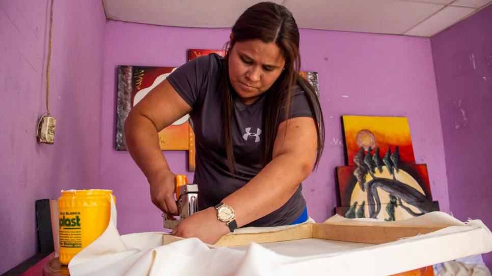 María José Mercado estira uno de los lienzos que pintará su esposo.
