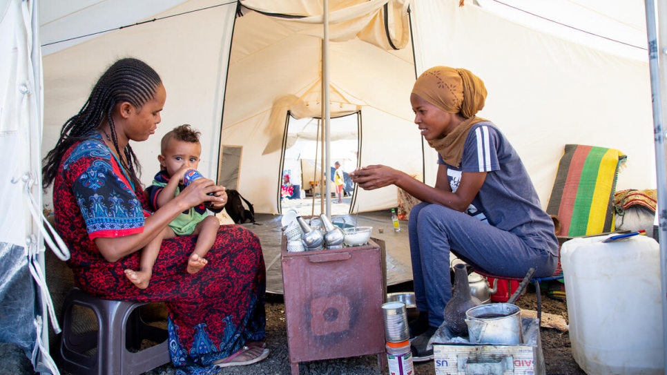 Mihret, de 25 años, charla con su tía mientras prepara el tradicional café etíope en su albergue en el asentamiento de Tunaydbah, en Sudán.