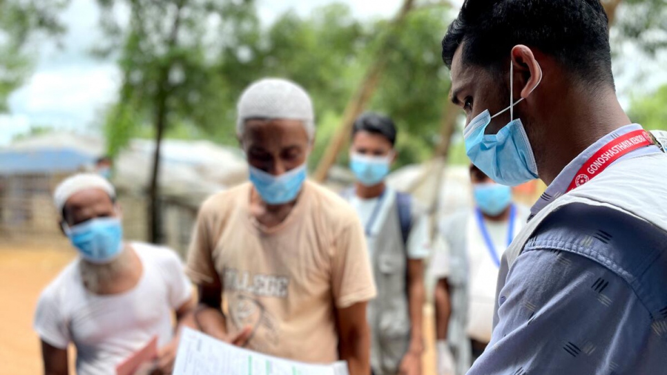 Humayun Kabir, un trabajador comunitario de salud en Bangladesh, ayuda a las personas refugiadas rohingyas que esperan recibir la primera vacuna de la COVID-19. 