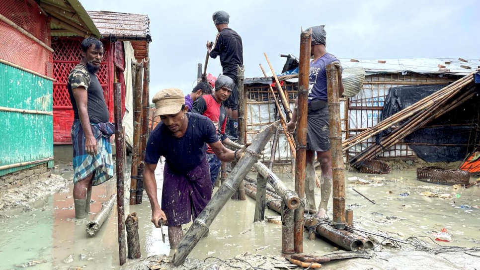 Voluntarios refugiados rohingyas trabajan para reconstruir un puente de bambú destruido por las inundaciones.