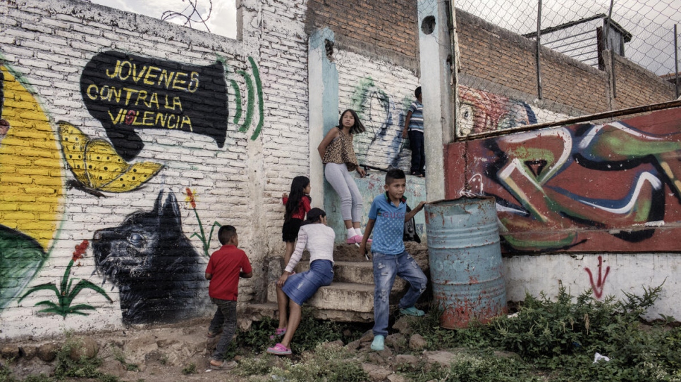 Niñas y niños junto a un mural creado como parte de las actividades de Jóvenes Contra la Violencia en la Nueva Capital, Honduras.