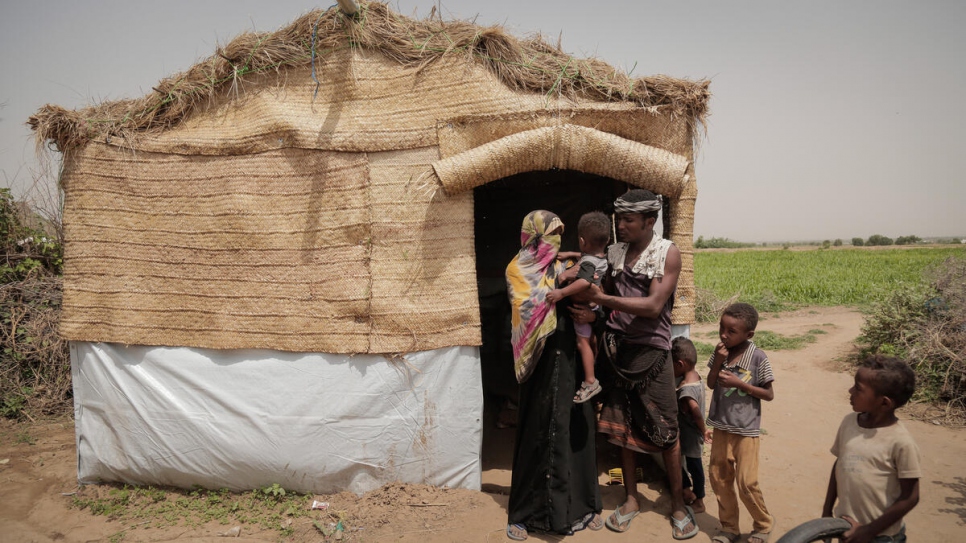Una familia desplazada junto al alojamiento proporcionado por la organización Jeel Albena en un asentamiento en Hudaydah, Yemen.