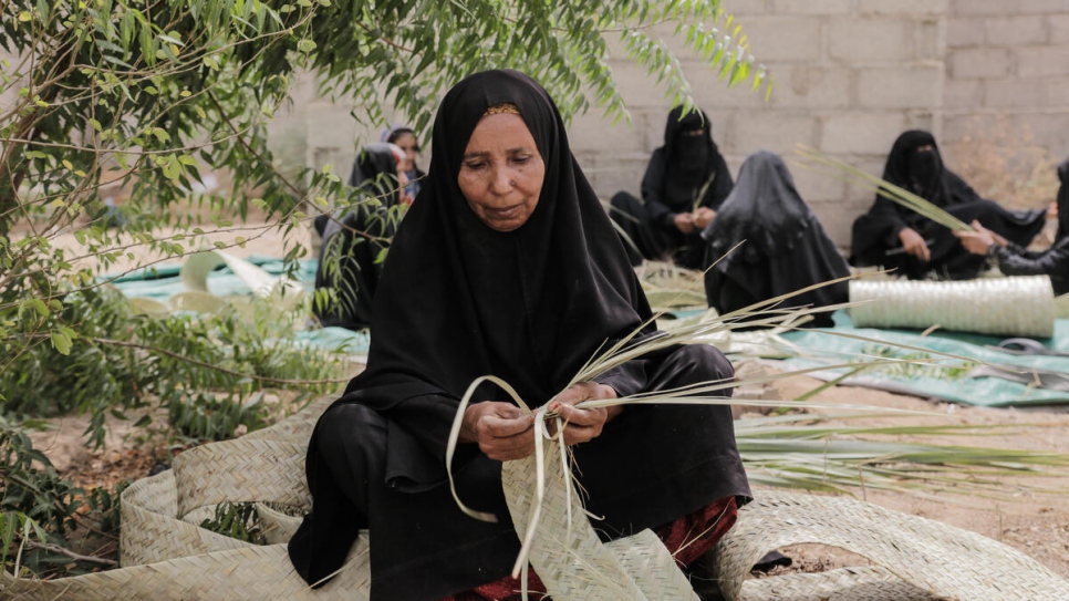 Una mujer yemení en un asentamiento para desplazados internos en Hudaydah entreteje hojas de palma que se usarán para construir alojamientos ecologícamente sostenibles.
