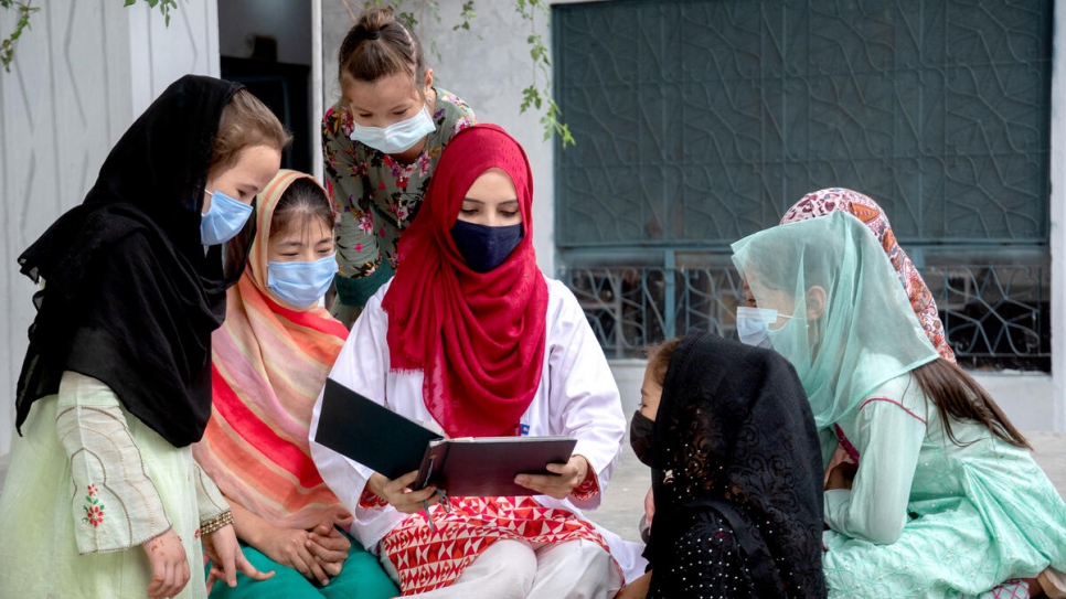 Mientras hojead un viejo álbum de fotografías, Saleema comparte con niñas refugiadas el camino que recorrió para convertirse en doctora.