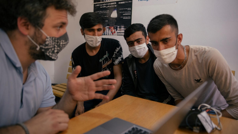 Nikola Kovačević se comunica con dos solicitantes de asilo afganos con la ayuda de un intérprete en el centro de recepción en Adasevci.