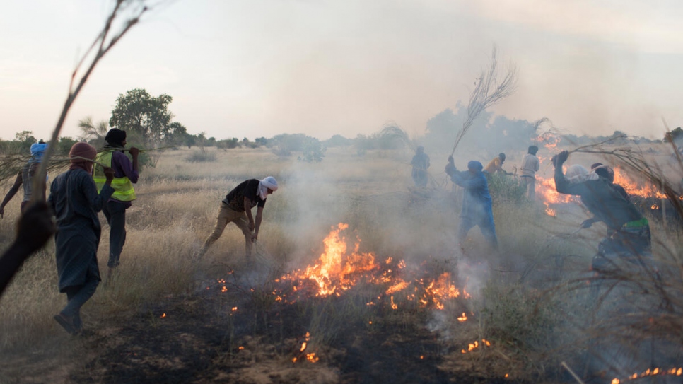 Integrantes de la Brigada de Refugiados contra Incendios usan ramas para apagar el fuego cerca de la frontera de Mauritania con Mali.