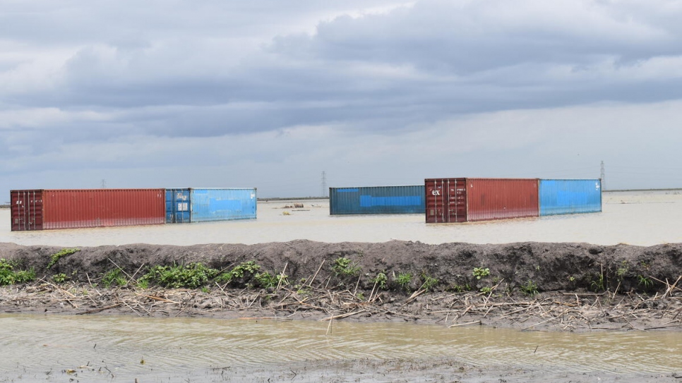 Los contenedores de ACNUR que sobrevivieron a las inundaciones en el campamento de Alganaa se pueden ver a través del campamento inundado.