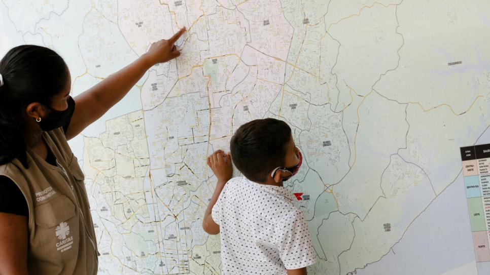 Lucetti y Keiver, su hijo de ocho años, observan un mapa gigante de Manaos que se encuentra en Caritas, su lugar de trabajo.