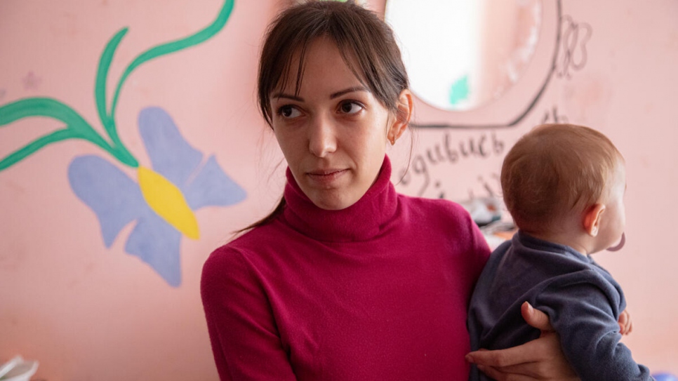 Oleksandra carga a su hija Polina, de siete meses, en su habitación en el dormitorio de la Universidad Estatal de Mukachevo.