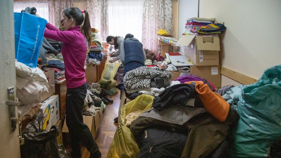 Oleksandra busca ropa de abrigo para sus hijas entre las donaciones apiladas en la Universidad Estatal de Mukachevo.
