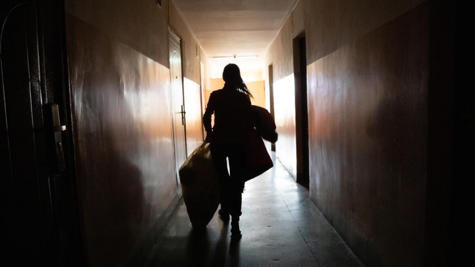 Oleksandra lleva mantas y ropa de abrigo a la habitación donde está viviendo con su familia en el dormitorio universitario.