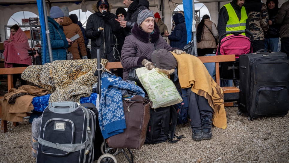 Las personas refugiadas soportan temperaturas debajo de los cero grados mientras se preparan para abordar los autobuses en el cruce fronterizo de Palanca, Moldavia.