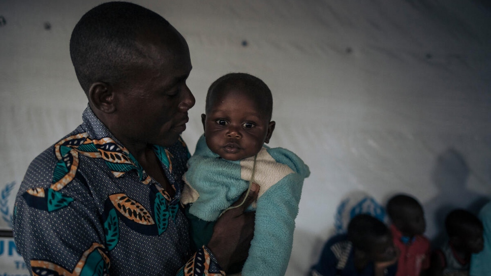 Firmin sostiene a su hijo mientras esperan para abordar en un vuelo desde Gbadolite, al norte de la República Democrática del Congo, hacia la República Centroafricana.