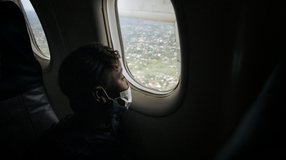 Un niño refugiado mira por la ventana del avión durante el vuelo de repatriación.