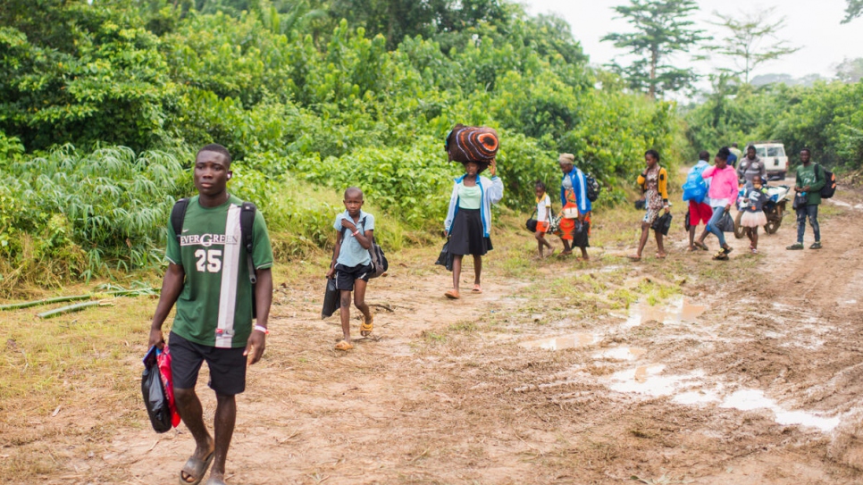 Las familias de Côte d'Ivoire recorren el camino que va del campamento de tránsito de Buutuo (Liberia) al banco del Río de Cestos, antes de volver a casa.