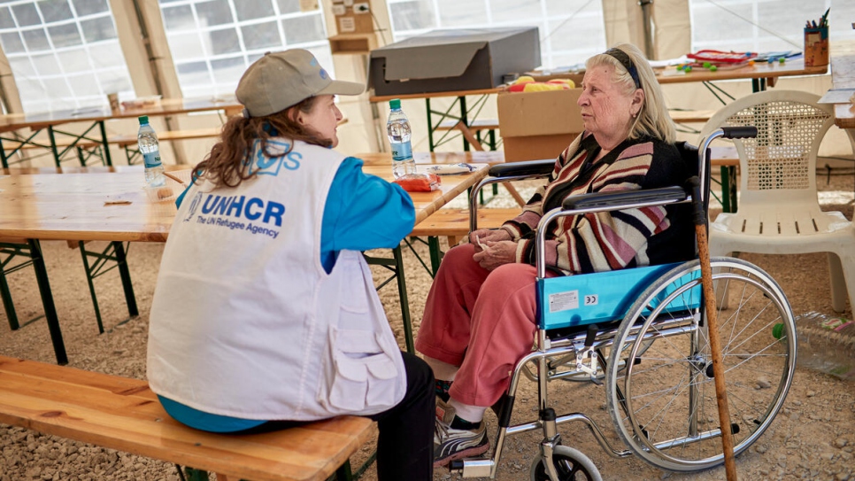 Una trabajadora de un socio de ACNUR consuela a Svetlana, de 83 años, en un área de descanso en Palanca, Moldavia.