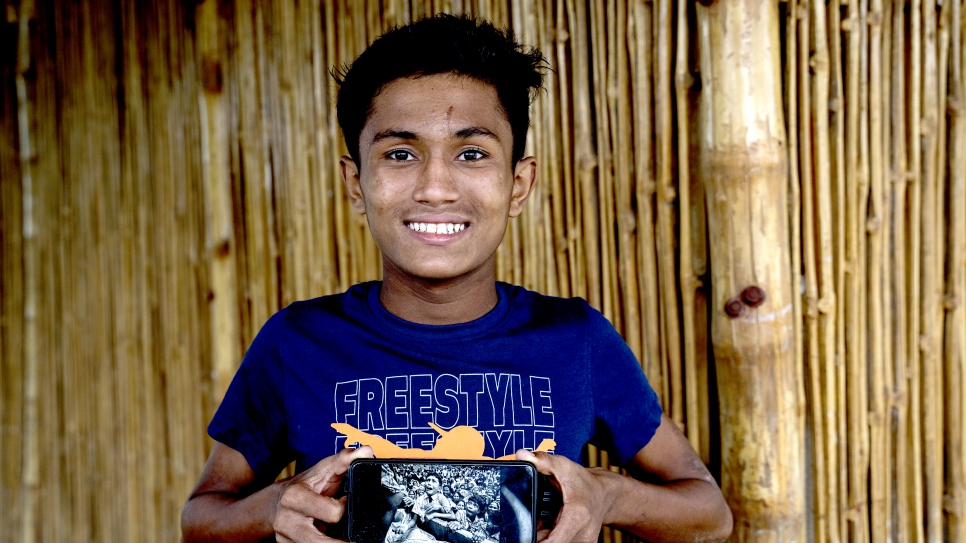 Hasson sostiene un teléfono móvil en el que se ve la fotografía que le hizo Kevin Frayer en 2017, poco después de llegar a Bangladesh con su familia.