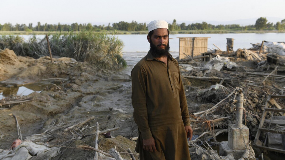 Saleem Khan, un granjero de 25 años, está de pie frente al sitio donde se encontraba su casa antes de haber sido arrasada por las inundaciones.