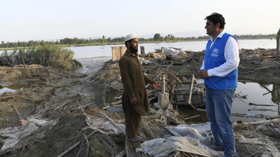 Saleem Khan charla con un trabajador de ACNUR. Su familia recibió una casa de campaña, pero sus cultivos fueron destruidos. Necesitan recursos monetarios para reconstruir su casa.