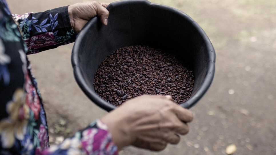 Carmen*, una solicitante de asilo nicaragüense de 38 años, sostiene granos de cacao secos después de haberles quitado la cáscara. Este es uno de los pasos para convertirlos en chocolate.