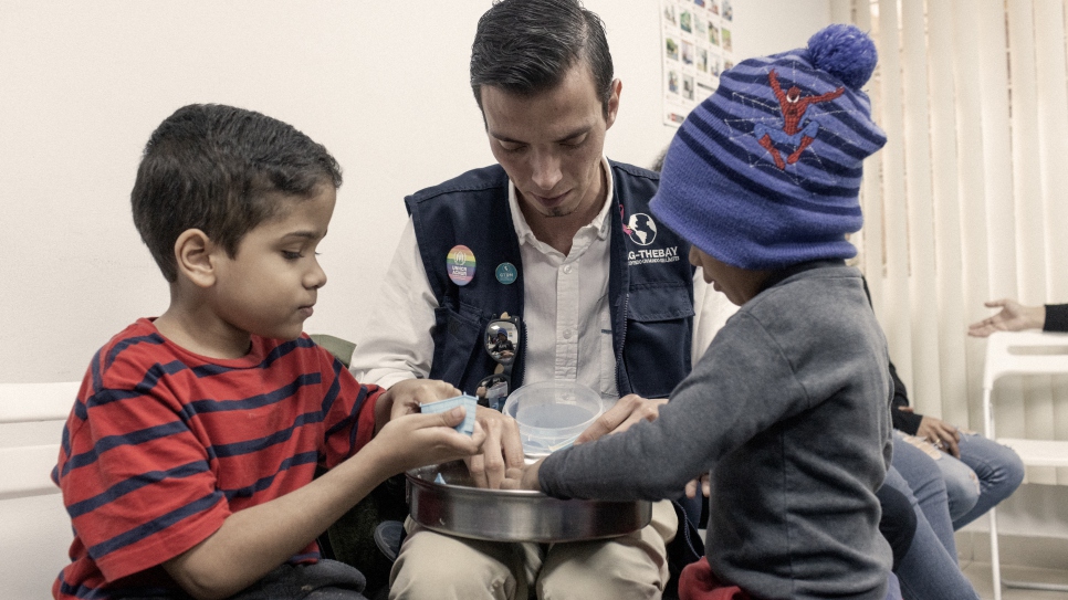 El presidente de Mag-TheBay, Daniel Tarazona, juega con dos niños en la sede de la organización en Lima.