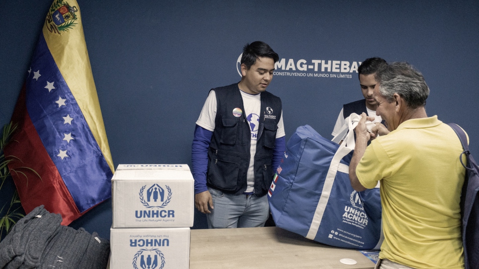Funcionarios de Mag-TheBay entregan kits de primera necesidad donados por ACNUR a beneficiarios de la organización.
