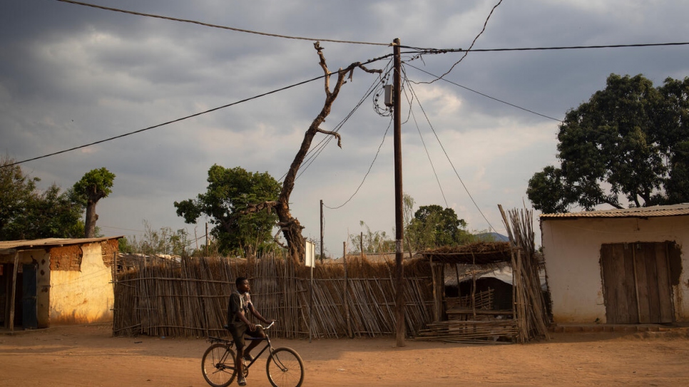 Un hombre pasea en bicicleta cerca de un poste de electricidad en el asentamiento de Marratane, donde viven alrededor de 9.200 personas refugiadas, principalmente de la República Democrática del Congo y Burundi.