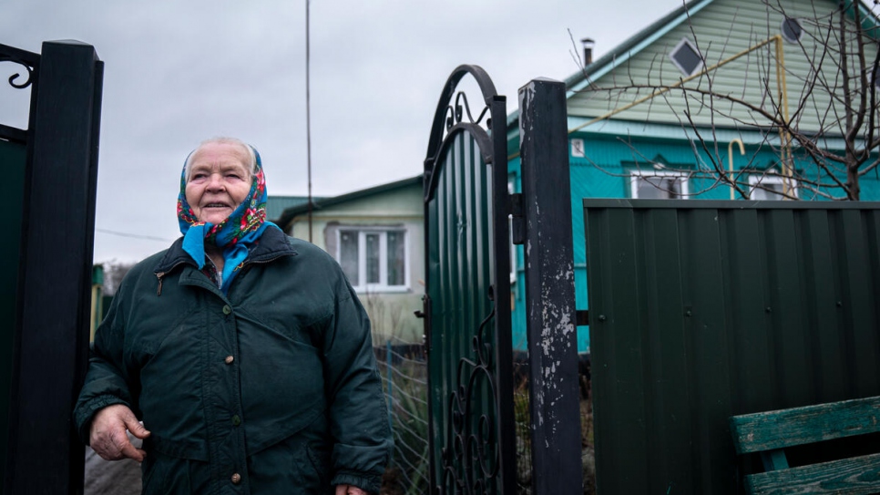 Kateryna frente a su casa, que sufrió graves daños durante los combates en el pueblo de Ozershchyna en marzo de 2022.