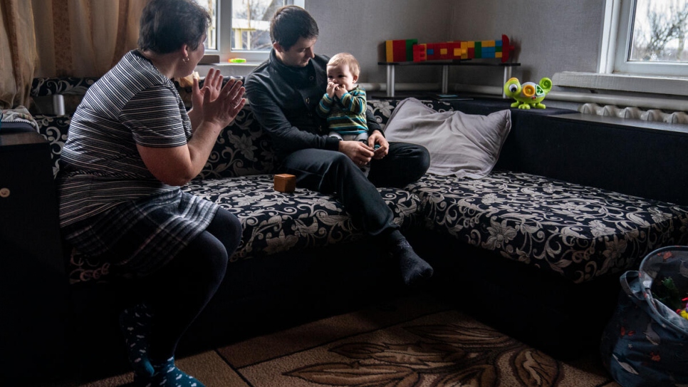Mykhailo, de 31 años, sostiene a Matvii mientras su suegra, Olena, de 51, intenta llamar la atención del bebé.