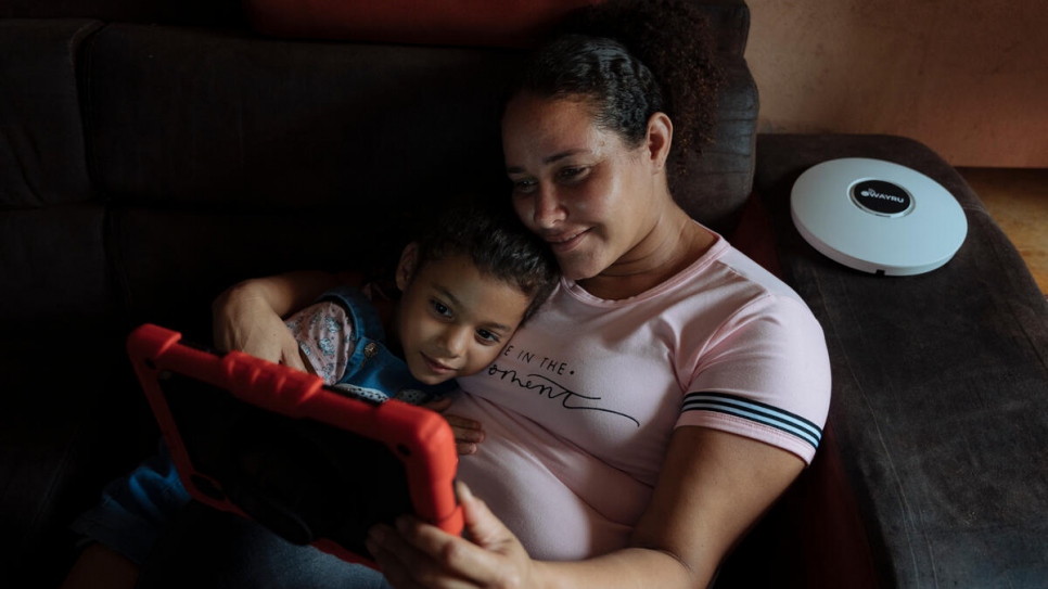 Gracias al nuevo servicio internet en la comunidad, Desiree – aquí con su hija menor Camila, de 6 años – ahora puede usar una tablet desde su casa.