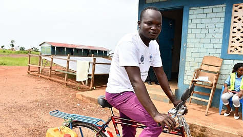 Thierry de 27 años, un refugiado de la República Centroafricana, recorre en su bicicleta el campamento de Inke, República Democrática del Congo, para promover buenas prácticas de higiene.
