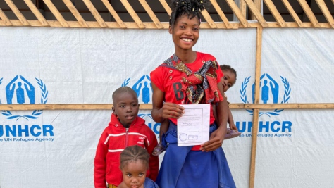 Mamie sostiene un documento que ayudará a su hijo a matricularse en la escuela primaria, que recibió en el Centro de Tránsito de Pweto, en la provincia de Haut Katanga, República Democrática del Congo.  