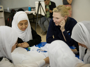 un grupo de niñas sentadas a una mesa junto a Cate Blanchett.