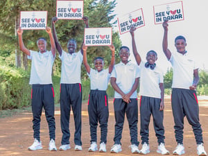 Seis jóvenes sonrientes que visten ropa deportiva, sostienen carteles que dicen "nos vemos en Dakar"