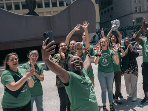 Un grupo de personas que visten camisetas verdes, levantan las manos